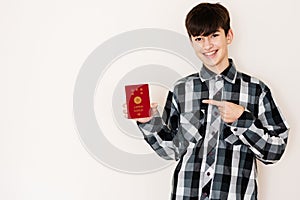 Young teenager boy holding Japan passport looking positive and happy standing and smiling with a confident smile against white