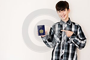 Young teenager boy holding Nauru passport looking positive and happy standing and smiling with a confident smile against white