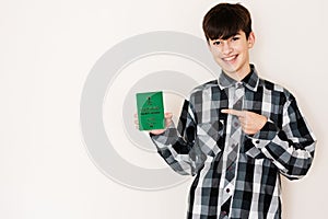 Young teenager boy holding Saudi Arabia passport looking positive and happy standing and smiling with a confident smile against