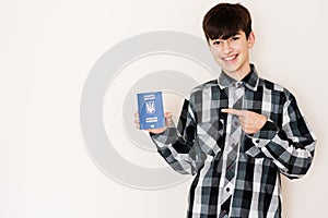 Young teenager boy holding Ukraine passport looking positive and happy standing and smiling with a confident smile against white