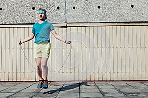 Young teenager boy jumping by the skipping rope on the house roof. Modern people fit challenges concept image