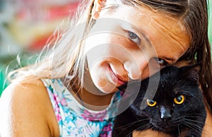 Young teenager brunette girl holding in her arms black cat.