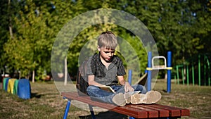 Young teenager doing homework sitting in park. Lifestyle video without stabilization.