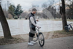 Young teenager enjoying a leisurely day outdoors with his bicycle in a park