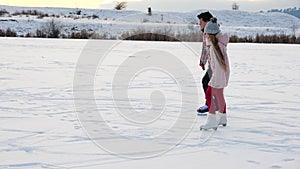 Young teenager girl and boy ice skating on lake against setting sun