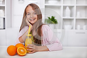 Young teenager girl with broad smile and freshly squeezed orange juice in the kitchen