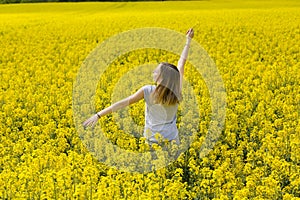 Young teenager girl enjoys the spring in the middle of jellow flowery field
