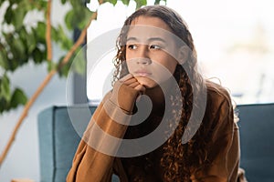 Young teenager girl feeling upset sitting on couch at home