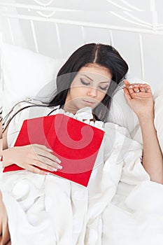 Young teenager girl fell asleep on the bed after reading a book