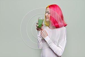 Young teenager girl with green vegetable smoothie drink, healthy vegan diet, copy space