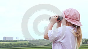 Young teenager girl looking into binoculars and watching the horizon in european countryside