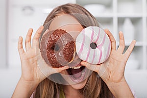 Young teenager girl making a google out of donuts - shouting wild and having fun