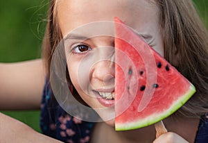 Young teenager girl playing with a slice of watermelon
