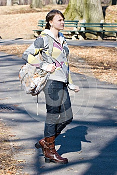 Young teenager girl standing holding a book bag