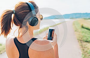 Young teenager girl starting jogging and listening to music using smartphone and wireless headphones. Active sport life concept