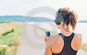 Young teenager girl starting jogging and listening to music using smartphone and wireless headphones. Active sport life concept