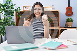 Young teenager girl studying using computer laptop smiling happy and positive, thumb up doing excellent and approval sign