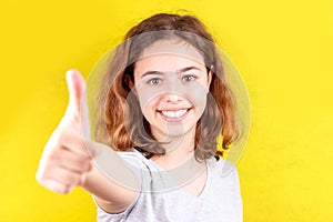 Young teenager girl with thumb up smiling at camera. Positive attitude