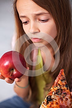 Young teenager girl undecided between healthy fresh apple and ap