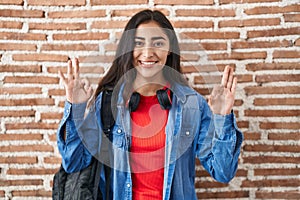 Young teenager girl wearing student backpack doing relax sign smiling with a happy and cool smile on face