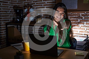 Young teenager girl working at the office at night smiling friendly offering handshake as greeting and welcoming