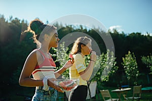 Young teenager girls friends outdoors in garden, eating watermelon.