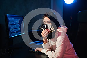 Young teenager hacker girl in hoodie holding credit card violating private password holding credit card in cybercrime