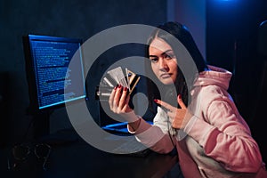 Young teenager hacker girl in hoodie holding credit card violating private password holding credit card in cybercrime