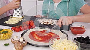 Young teenager hands making pizza in the kitchen - close up