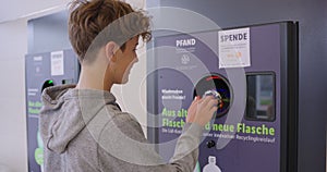 A young teenager hands plastic empty bottles into a machine in exchange for money in Germany. plastic recycling