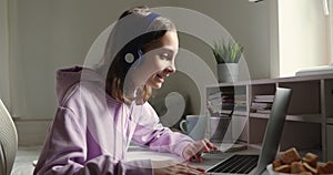 Young teenager in headphones greeting teacher at online lecture.