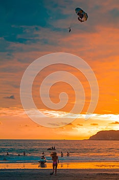 Young teenager running towards a beach full of tourists on a beautiful afternoon on the beach of the tropical Pacific in the