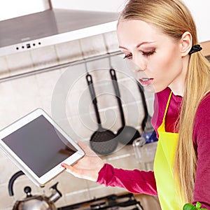 Young teenager woman holding tablet in kitchen