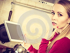 Young teenager woman holding tablet in kitchen