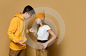 Young teens boy and girl in comfortable clothing, hats and sunglasses standing and communicating with each other