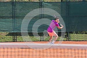 Young tennis player hitting the ball by backhand