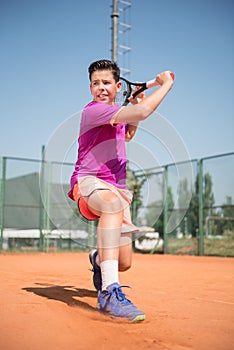 Young tennis player playing backhand and glide on a sunny day.