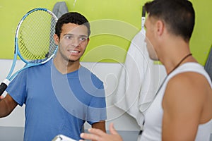 young tennis player talking to coach in changing room