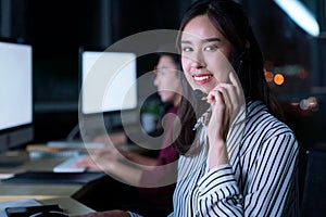 Young Thai Asian customer services care operators working night shift in call center for helping assistance client in workplace at