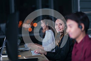 Young Thai Asian customer services care operators working night shift in call center for helping assistance client in workplace at