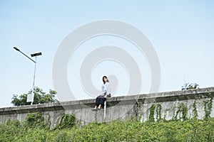 Young thai asian woman sitting on the wall