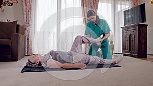 Young therapist exercising with older female patient in nursing home