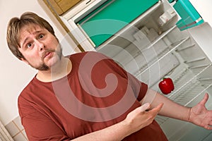 Young thick man in front of a fridge with one paprika inside