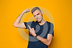 Young thin handsome guy shows on biceps of arm