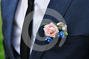 A young thin man in a classic suit with a tie and a white shirt and a rose in his buttonhole