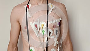 Young thin man on white background with holter monitor connected to his chest