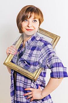 Young thin Woman peers out from the photo frame wearing blue checkered cotton shirt, over white background