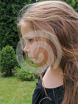 Young thinking girl in garden, standing and waiting,  think about something