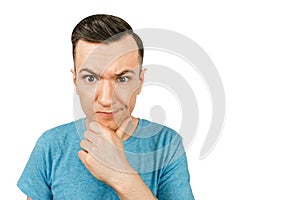 Young thinking man dressed in a blue t-shirt on a isolated white background