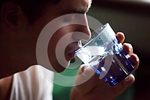 Young thirsty dehydrated man drinking water quenching thirst, cl photo